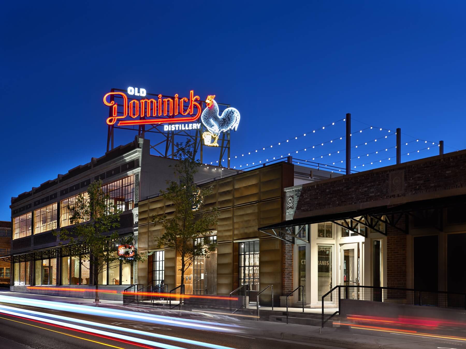 Exterior of Old Dominick Distillery with neon sign lit up at night.