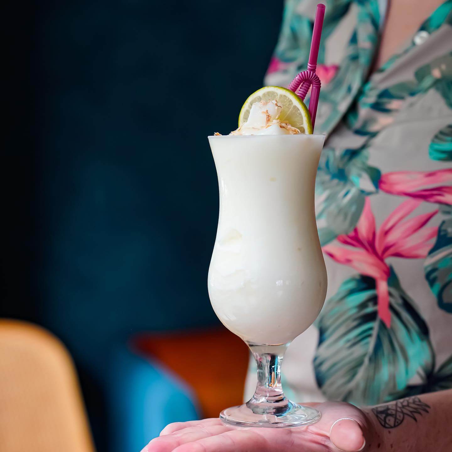 person in tropical print shirt holding a frozen cocktail