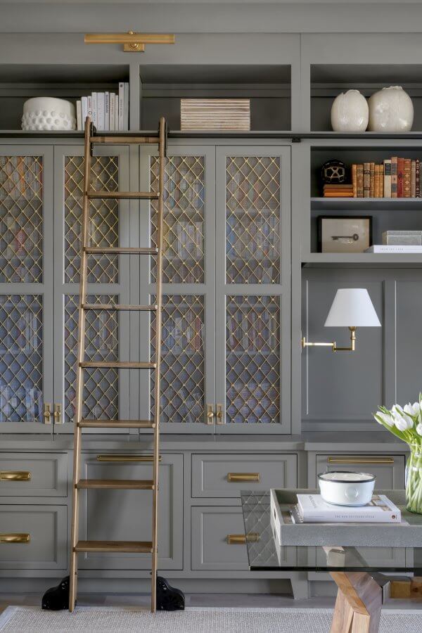 Bookshelves with a ladder near a glass desk.
