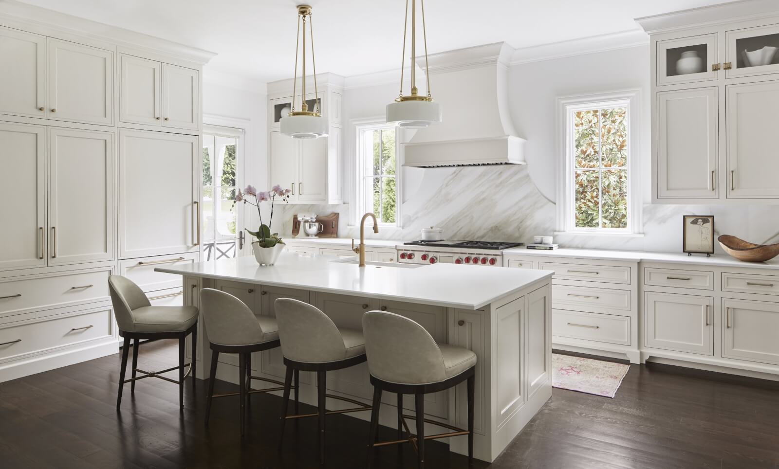 White kitchen with marble backsplash and dark wood flooring.