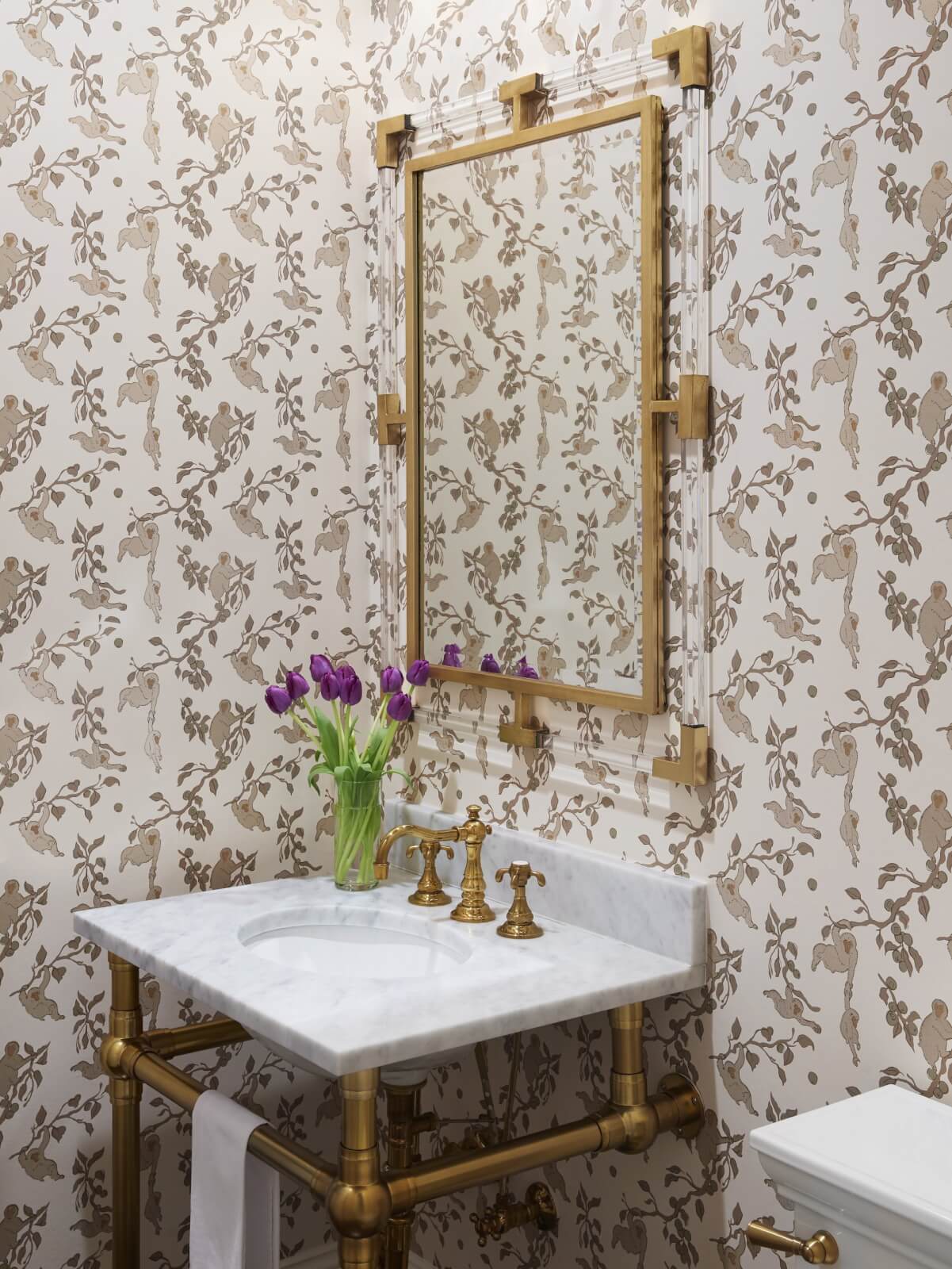 Gold-embellished powder room with purple tulips on the bathroom sink.