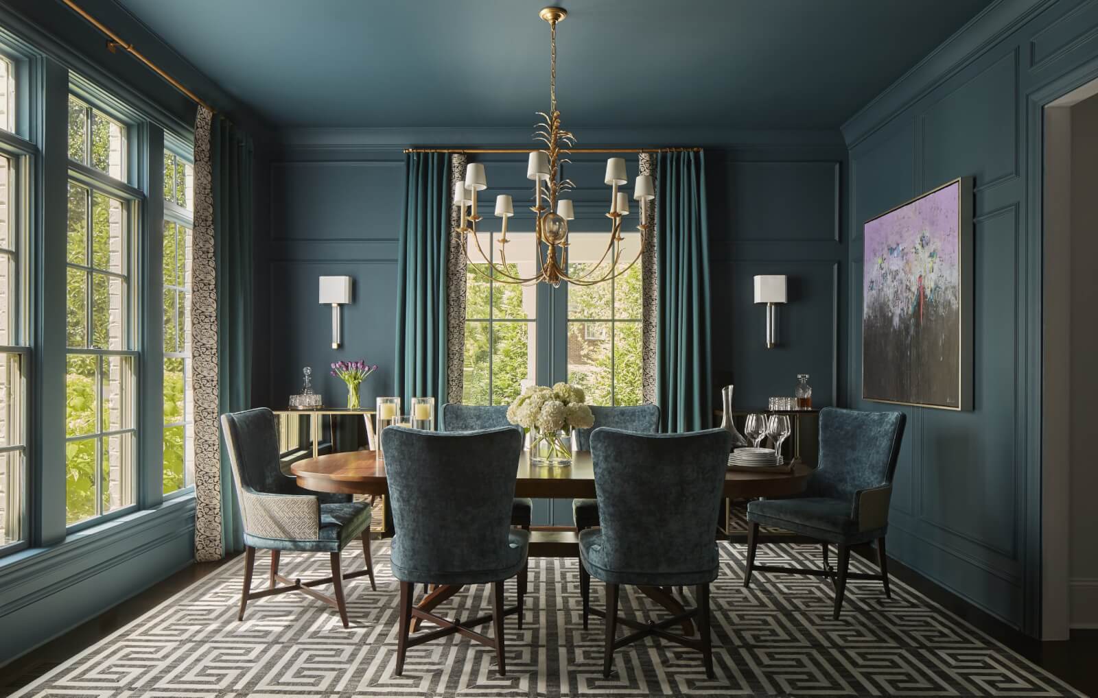 Teal-themed dining room with large round table and chairs.
