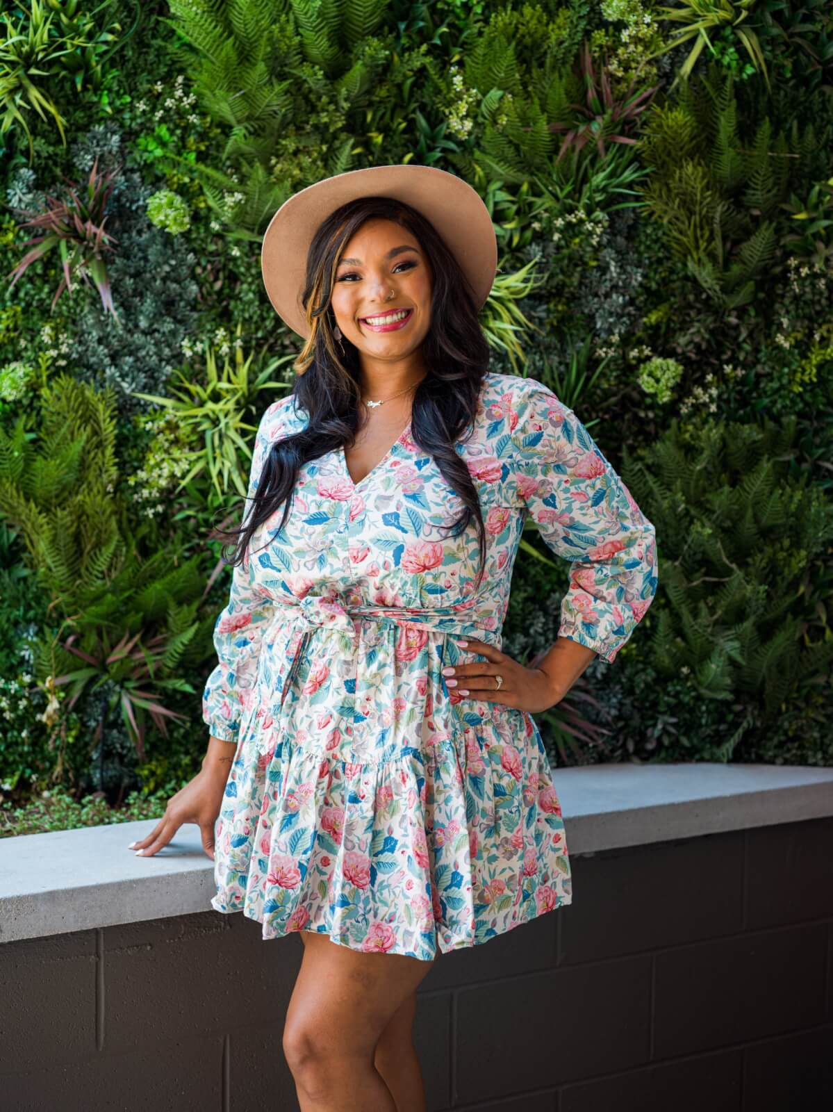 young woman with dark hair posing in floral dress and hat