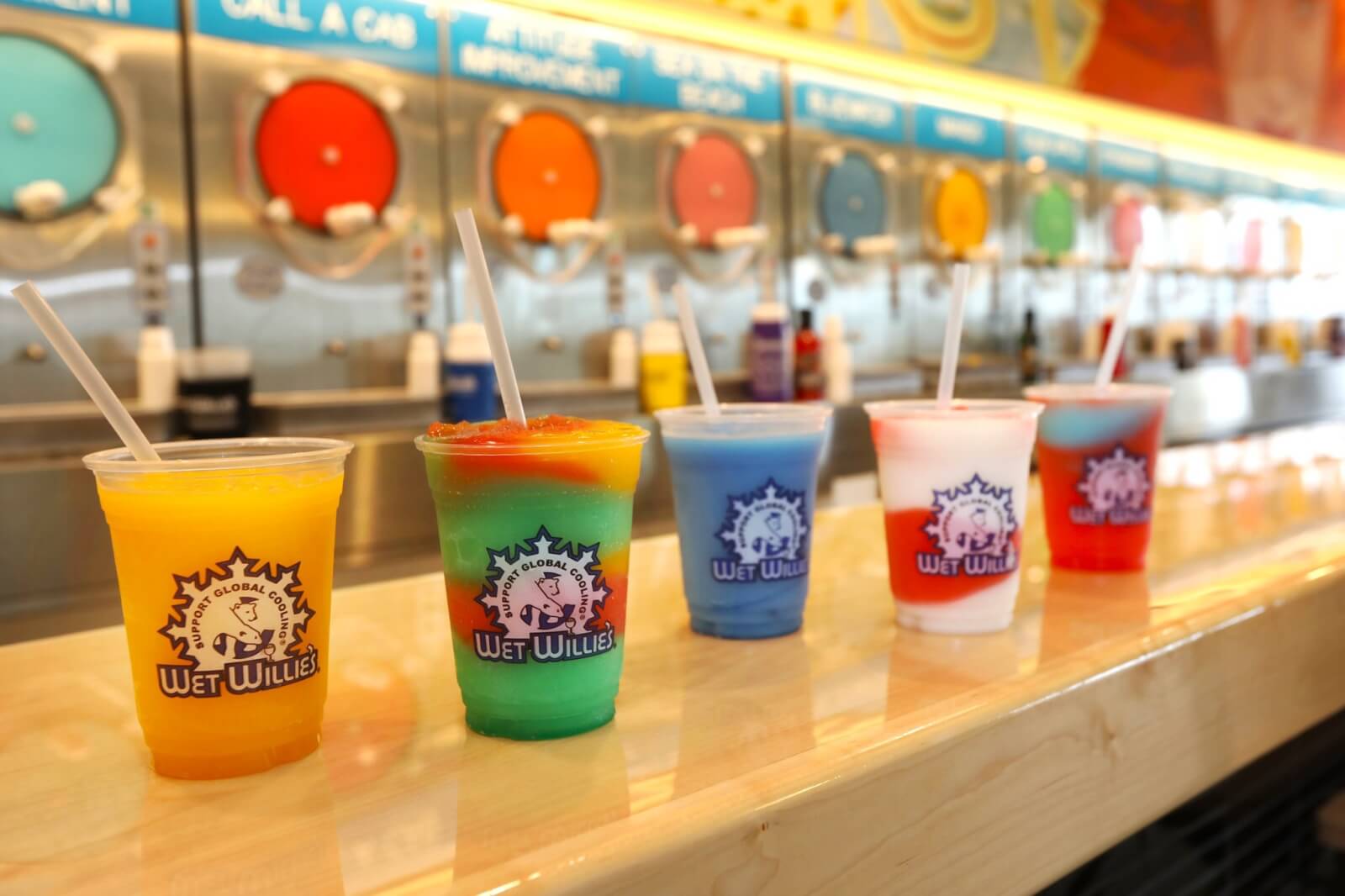 colorful frozen drinks lined up on a bar