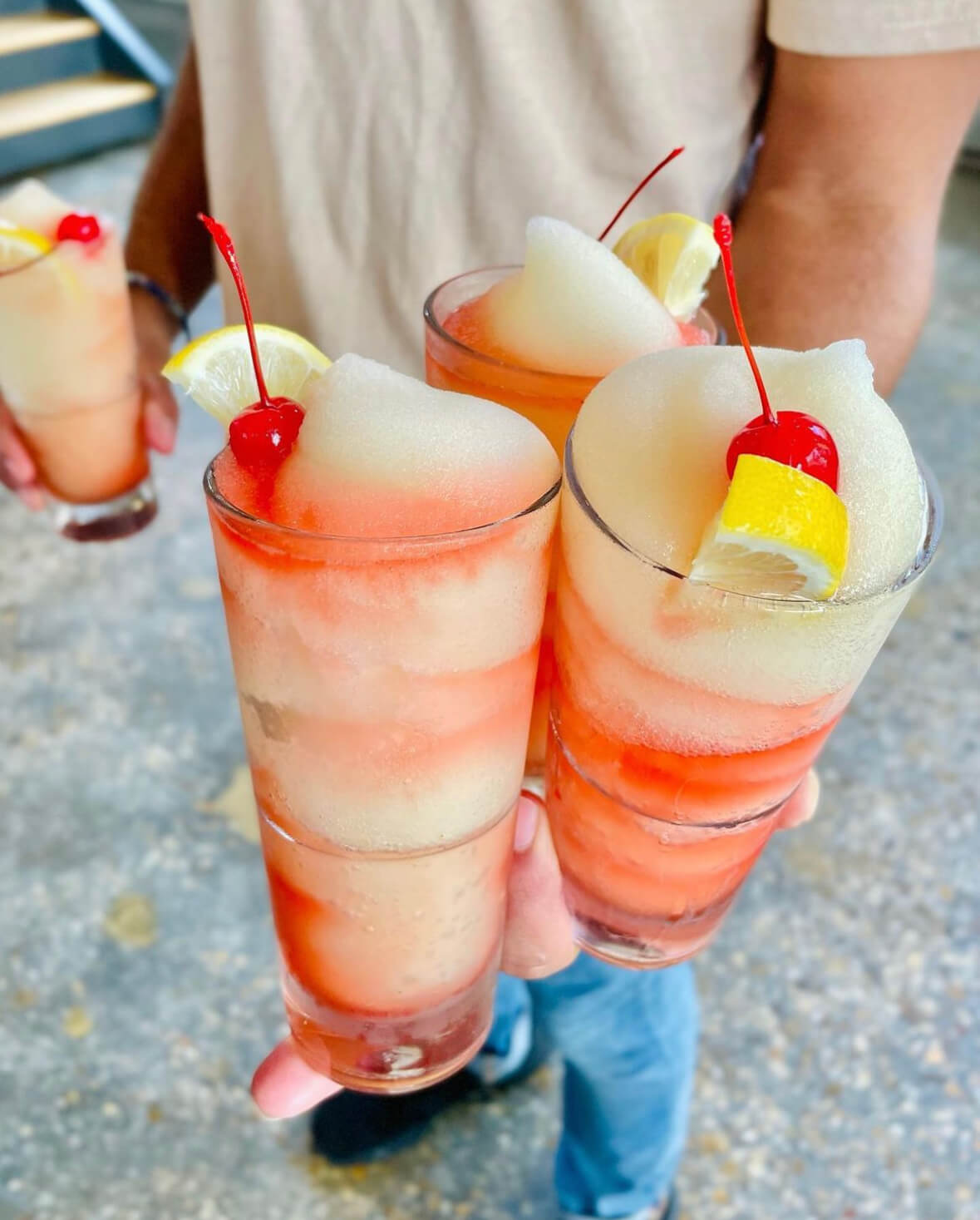 man holding four large frozen cocktails