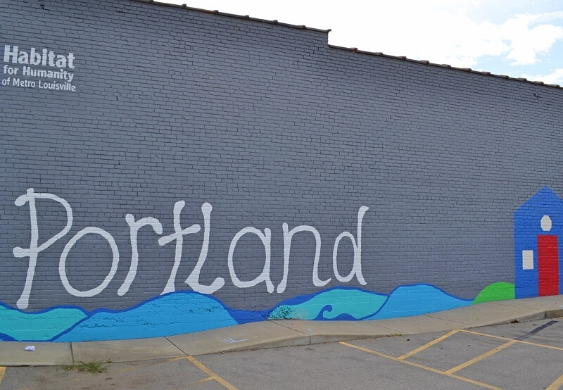 'Portland' mural on the side of a gray brick building.