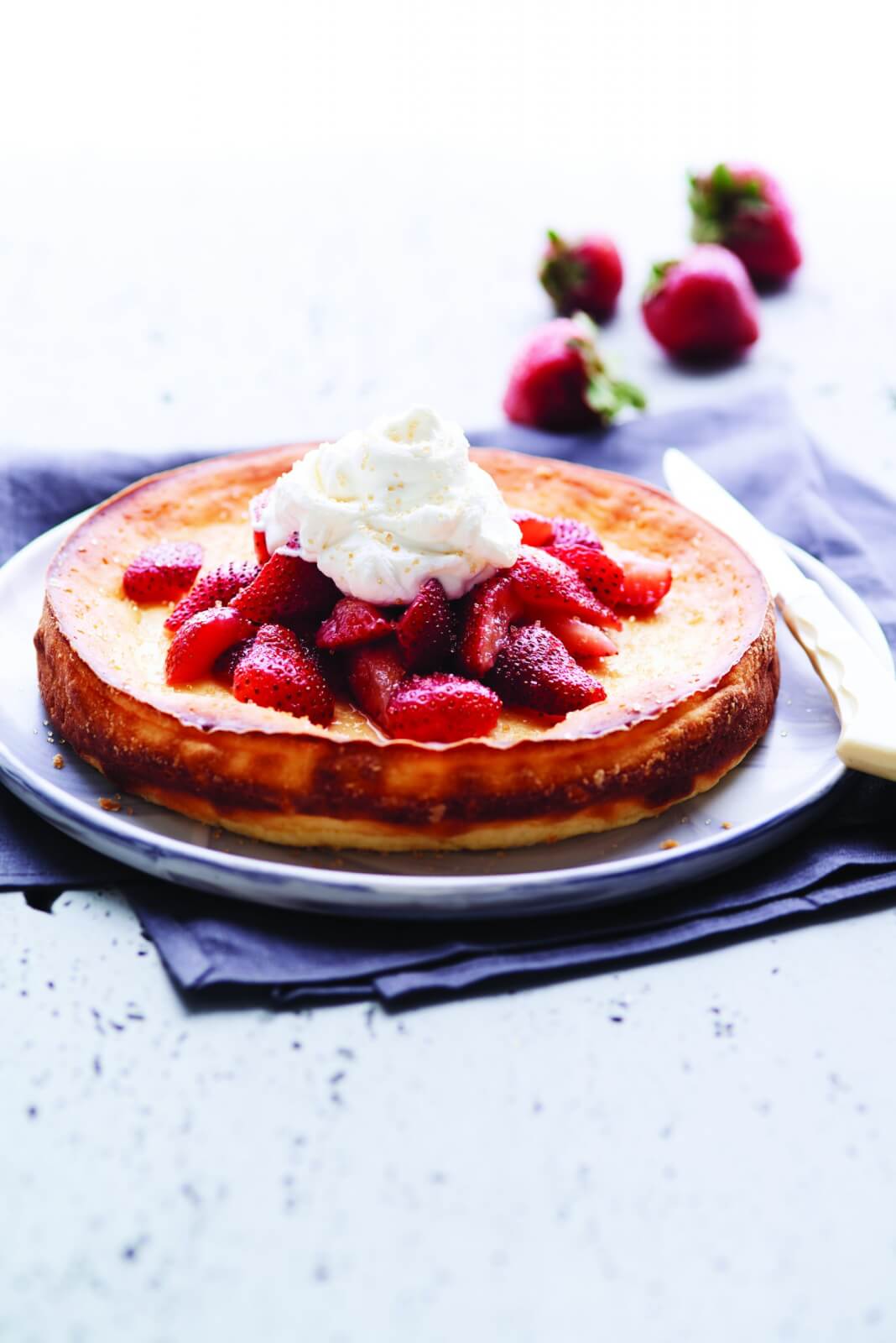 Mini ricotta cake topped with fresh strawberries and whipped cream.