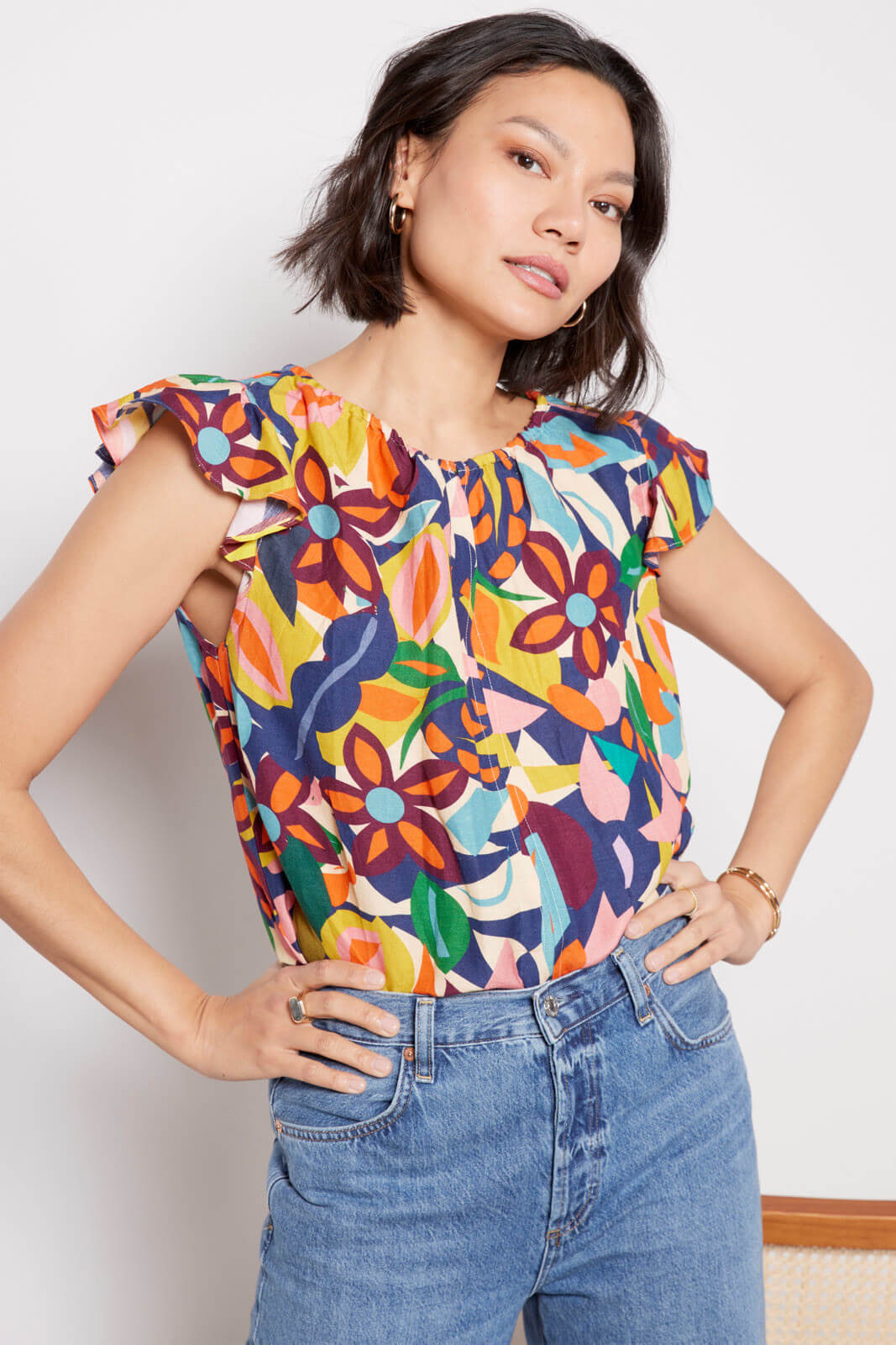 Model in colorful floral blouse and denim jeans.
