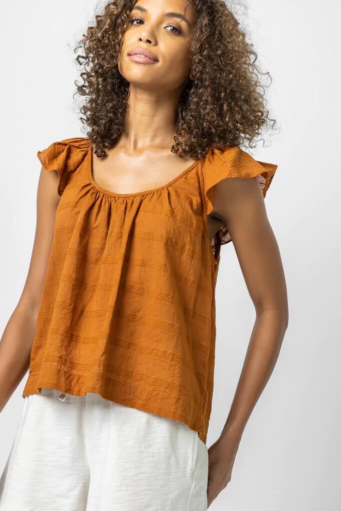 Model wearing orange crop top with ruffle sleeves.