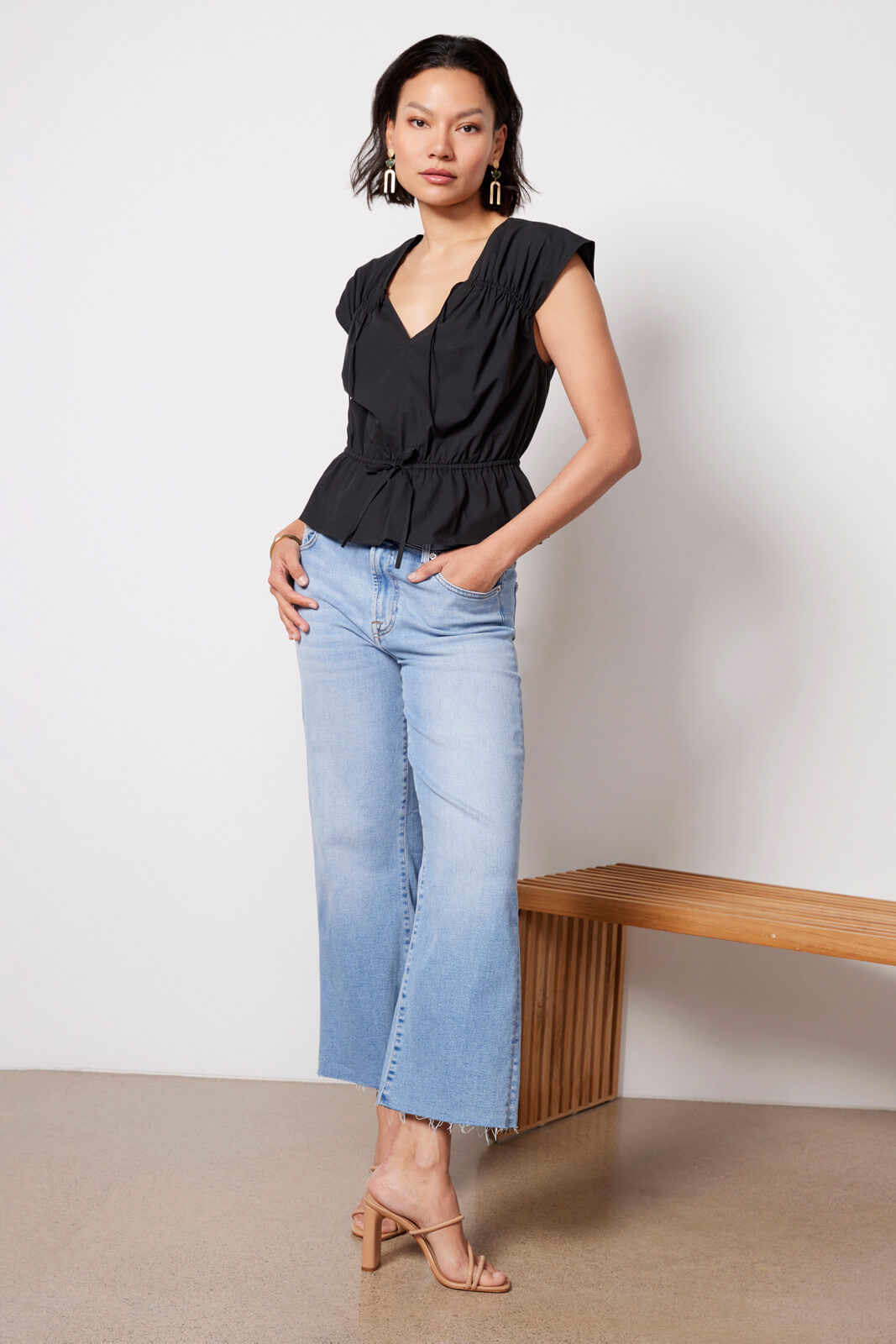 Model wearing black Savi top with denim flare jeans and nude heels.