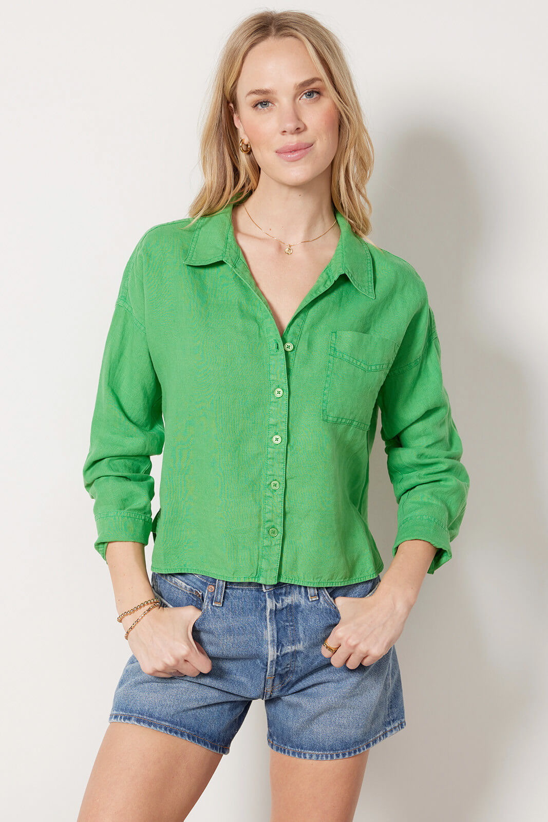 Model in jean shorts and green cropped collared shirt.