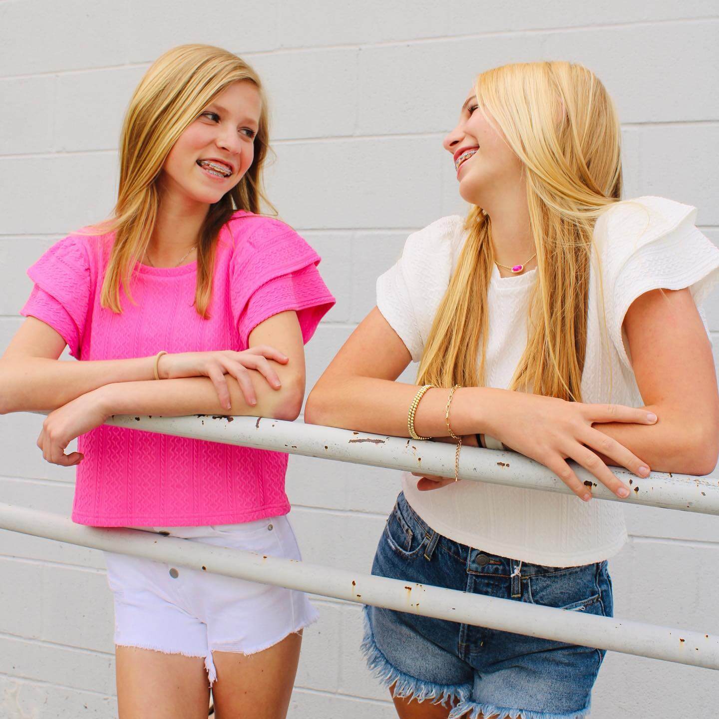 Two blond teenagers smiling at each other