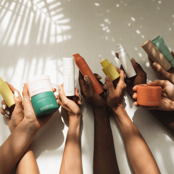 arms of different skintones holding colorful skincare products